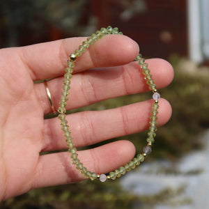 Hand holding a faceted handmade Peridot and Labradorite gemstone bracelet, emphasizing its sparkling beads and intricate design.