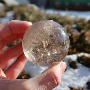 Rauchquarz Kugel – Natürliche Kristallkugel 48mm Durchmesser Nr. 47 im Sonnenlicht, reflektiert warm und beruhigend.