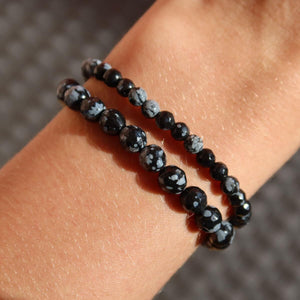 Faceted snowflake obsidian gemstone bracelet with black and white patterns displayed on a wrist.