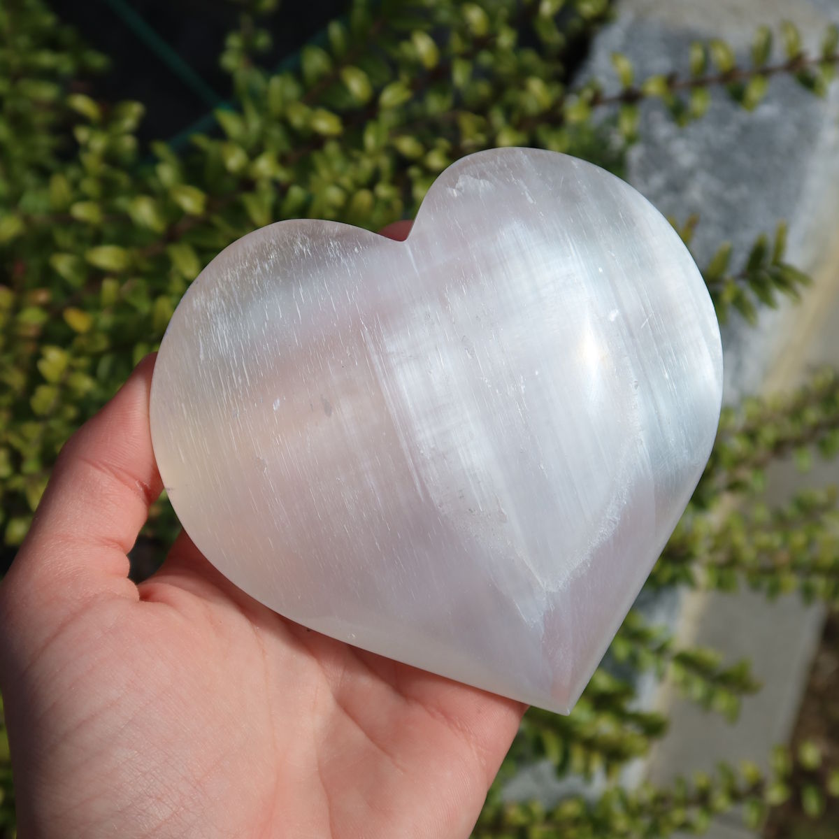 Selenit Herz - Handschmeichler - 10cm - Schutzstein für Stabilität und Nervenstärkung in Hand gehalten.