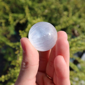 Hand holding a 30mm Selenite crystal sphere, a light-bringing and protective stone, ideal for purchase online at Steinwelten.