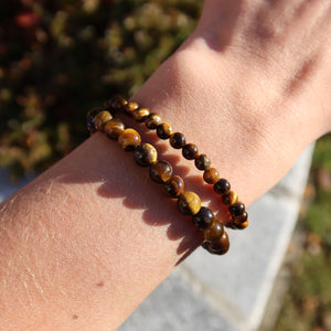 Tigerauge Edelstein Armband für schmale Handgelenke in Varianten 4-6 oder 8mm, getragen am weiblichen Handgelenk, glänzend im Sonnenlicht.