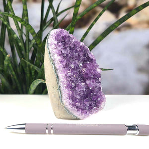 Uruguay Amethyst Mini Geode - 13x8x7cm - Harmonie und Entspannung – extra dunkler Qualität - NR 31 next to a pen on a table.