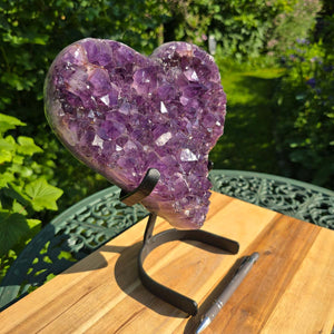 Amethyst Druse Amethyst Geode in Herzform mit Metallsockel 26x23x15cm - NR-22 auf einem Tisch mit Naturhintergrund.