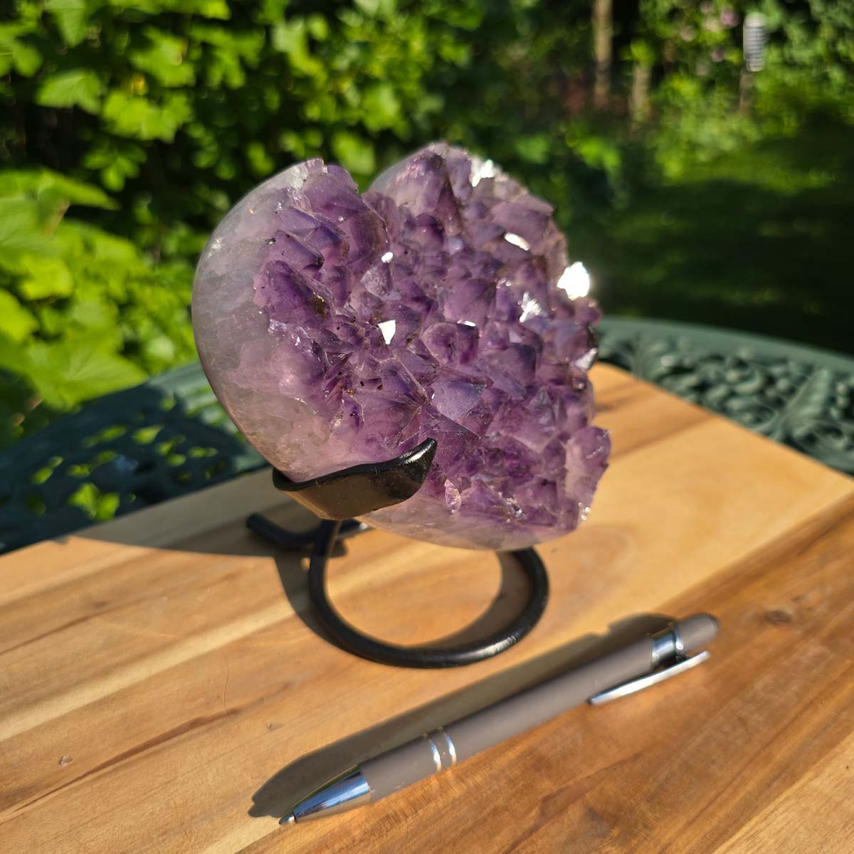 Amethyst Druse Amethyst Geode in Herzform mit Metallsockel 15x15x12cm - NR-41 auf Holzständer im Freien.