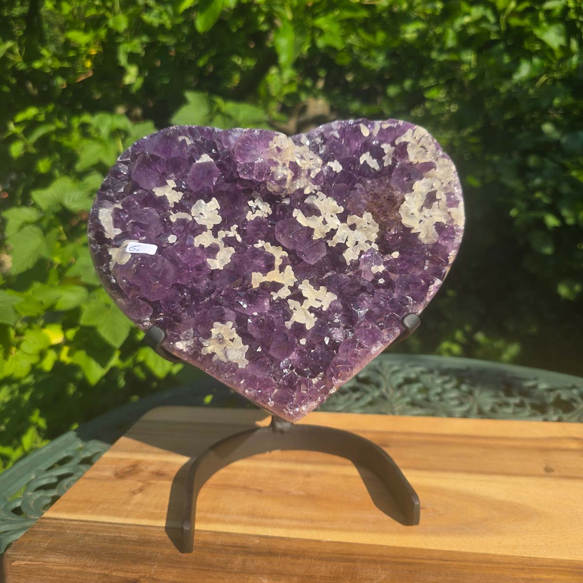 Amethyst Druse Amethyst Geode in Herzform mit Metallsockel 22x20x12cm - NR-6 auf einem Tisch im Freien