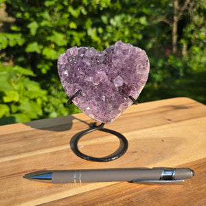 Amethyst Druse Amethyst Geode in Herzform mit Metallsockel 12x9x8cm - NR-49 auf einem Holzuntergrund.