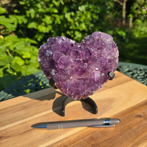 Amethyst Druse Amethyst Geode in Herzform mit Metallsockel 15x14x9cm - NR-42 auf einem Tisch mit Stift