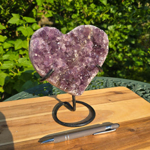 Amethyst Druse Amethyst Geode in Herzform mit Metallsockel 18x16x10cm - NR-45 auf einem Tisch im Freien.