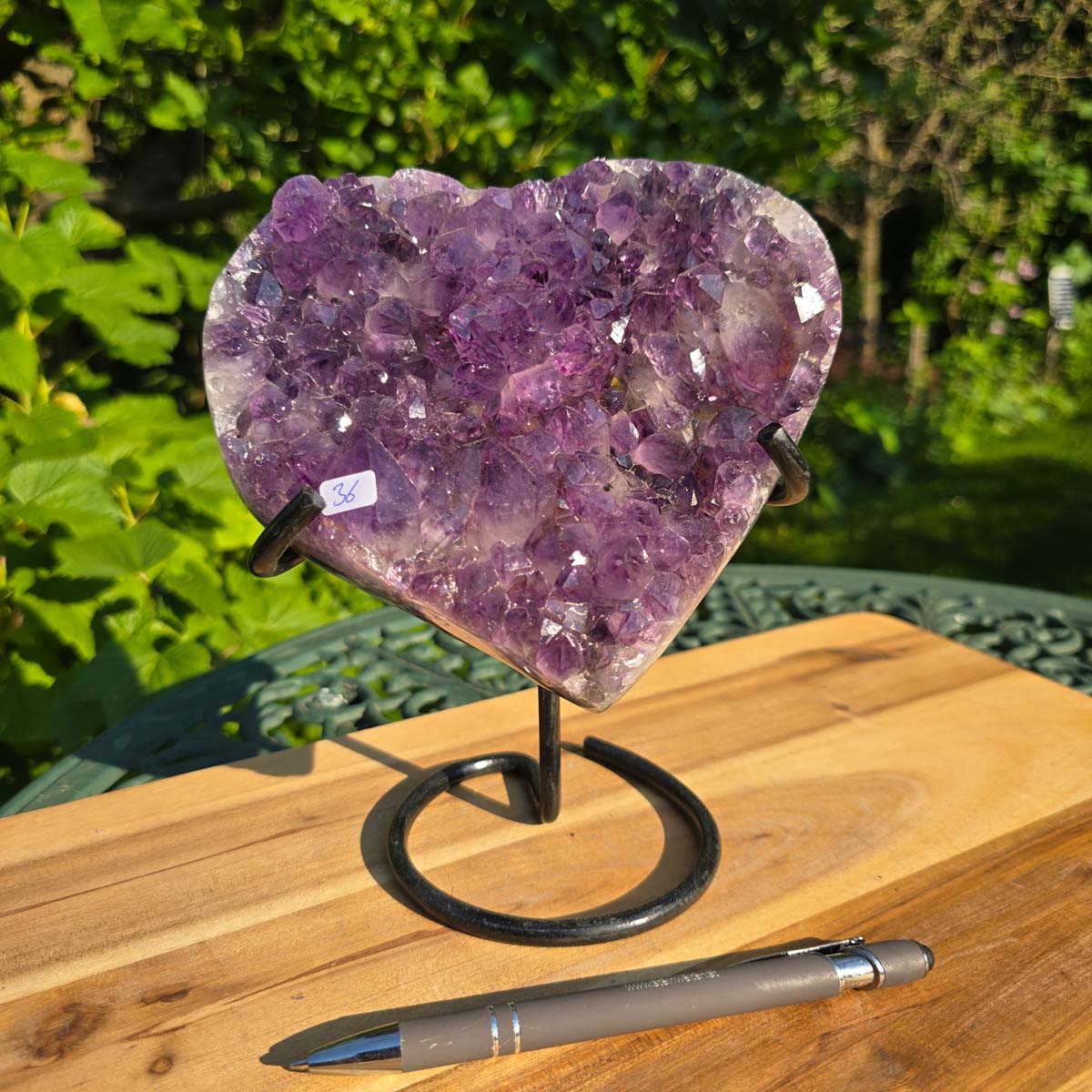 Amethyst Druse Amethyst Geode in Herzform mit Metallsockel 19x16x11cm - NR-36 auf einer Holzoberfläche.