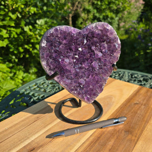 Amethyst Druse Amethyst Geode in Herzform mit Metallsockel 18x16x10cm - NR-43 auf einem Tisch im Freien