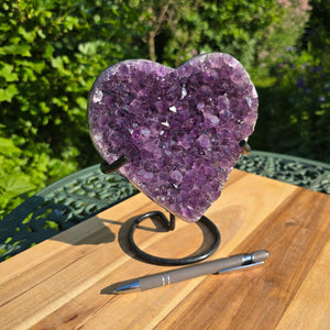 Amethyst Druse Amethyst Geode in Herzform mit Metallsockel 18x16x10cm - NR-43 auf einem Holz-Tisch präsentiert