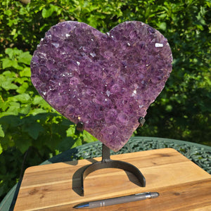 Amethyst Druse Amethyst Geode in Herzform mit Metallsockel 31x28x12cm - NR-24 auf einem Holzständer.