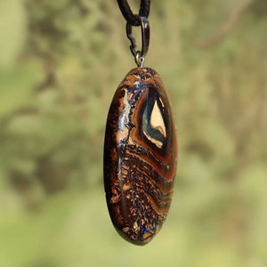 Boulder Opal Anhänger - Positivität und Freude - Nr. 44, handgeschliffener Stein mit einzigartigem Muster und echter Silberöse in Naturkulisse.