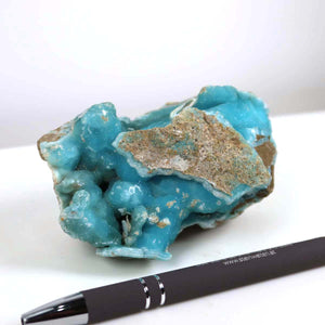 Raw Hemimorphite stone with vibrant turquoise color, measuring 9x6x5 cm, unique collectible mineral next to a pen for size reference.