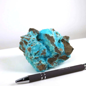 Raw Hemimorphit mineral with turquoise blue hues measuring 9x8x5 cm, displayed next to a pen for scale.