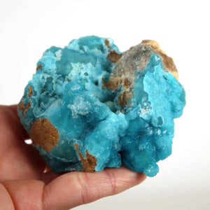 Hemimorphite raw stone in vibrant turquoise blue with natural crystal structure, unique collector's mineral in a hand. Unpolished, natural beauty.