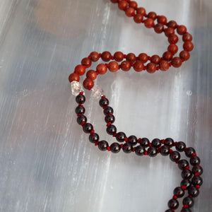 Mala Kette handgemacht aus rotem Granat, Jaspis und Herkimer Quarz, für Erdung und Stabilität, auf einer weißen Unterlage.