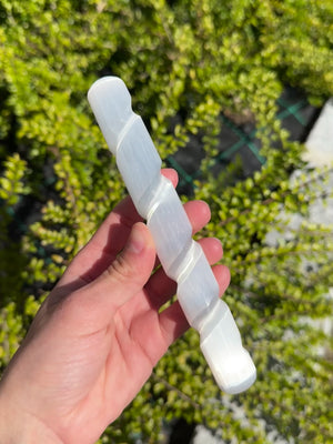 Echter Selenit Massagestab & Zauberstab - Griffel mit Spirale- 15cm in der Hand vor grünem Hintergrund.