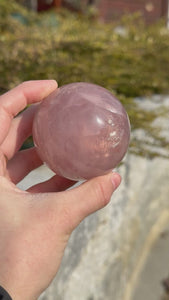 Hand holding a polished rose quartz sphere, highlighting its gentle pink hue and smooth surface, available to buy online at Steinwelten.