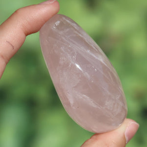 Rosenquarz Handschmeichler - Selbstliebe und Harmonie - Nr. 28, zarter rosa Edelstein in Hand gehalten.